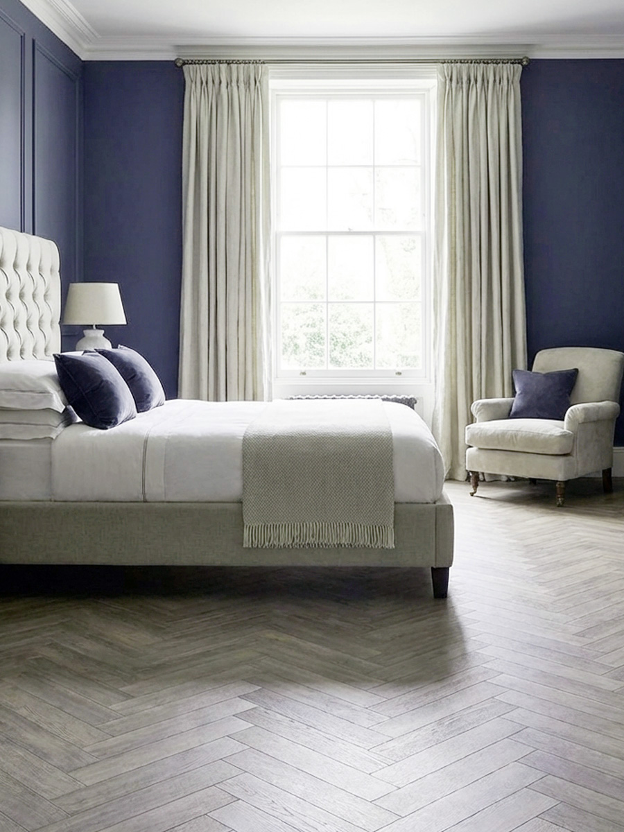 blue bedroom with blue painted walls and herringbone wood flooring